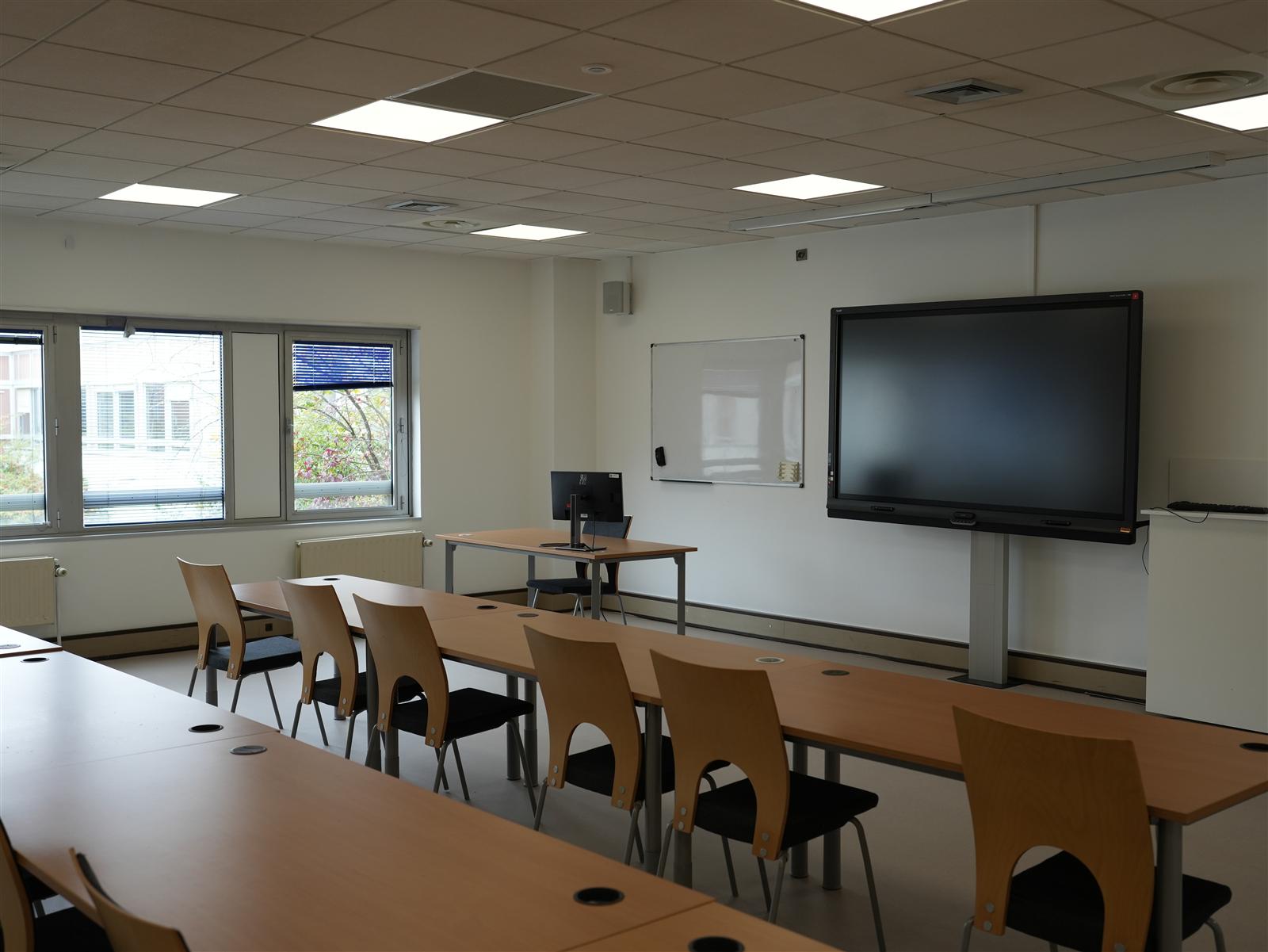 Salle de cours du centre, tables en U face à un écran interactif